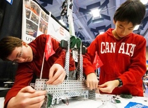 Two young boys building a robot in a robotics competition